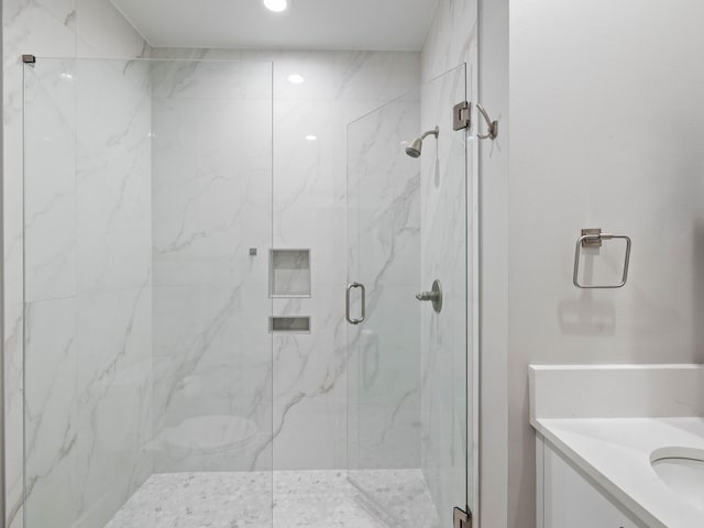 full bathroom with a marble finish shower and vanity