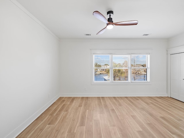 empty room with baseboards, visible vents, and light wood finished floors