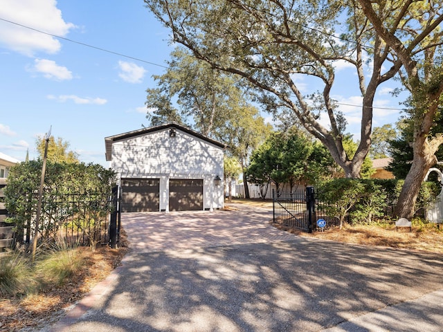 view of property exterior featuring a garage, a gate, fence, and an outbuilding