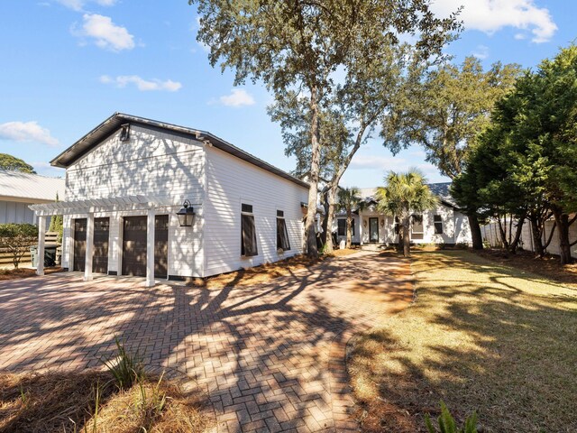 view of side of home with a garage, decorative driveway, and a pergola