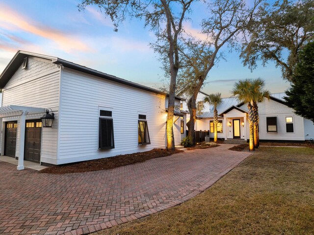 view of home's exterior featuring a garage, a yard, and decorative driveway