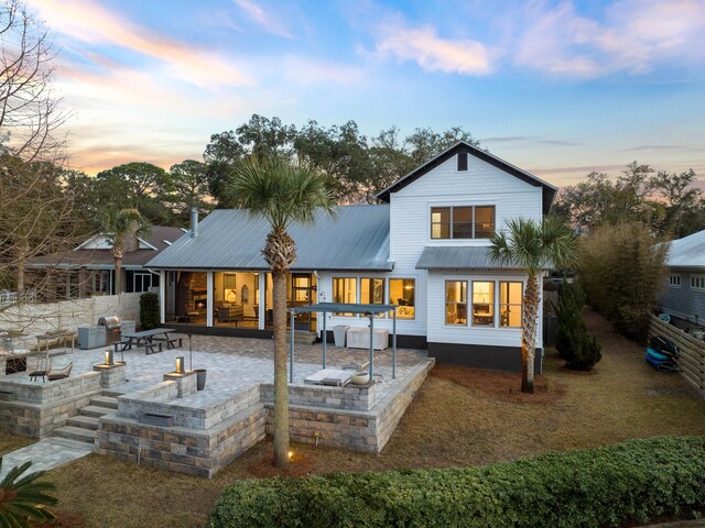 back of property with an outdoor fire pit, a patio area, and metal roof