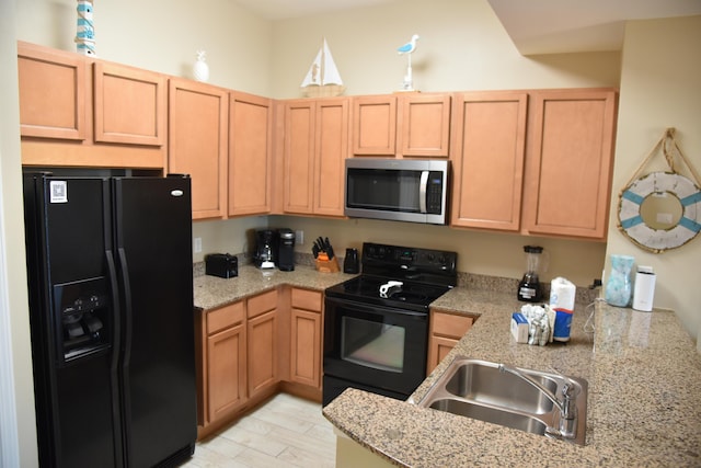 kitchen featuring sink, light stone counters, kitchen peninsula, light hardwood / wood-style floors, and black appliances