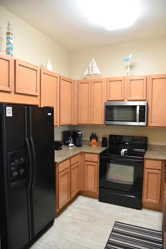 kitchen with light stone counters, light hardwood / wood-style flooring, and black appliances