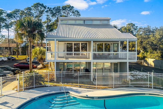 back of house with a fenced in pool and a balcony