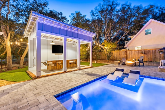 view of pool featuring an outdoor fire pit, exterior bar, an outbuilding, and a patio