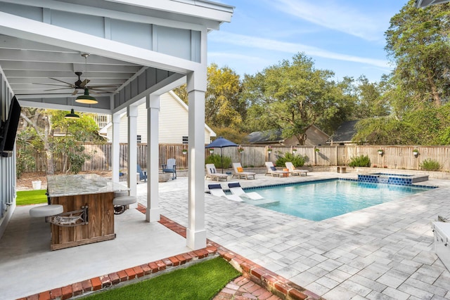 view of swimming pool with ceiling fan, a bar, and a patio