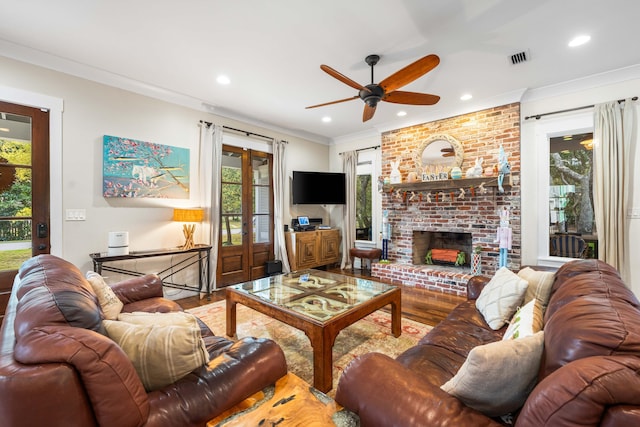 living room featuring hardwood / wood-style flooring, ceiling fan, a brick fireplace, french doors, and ornamental molding