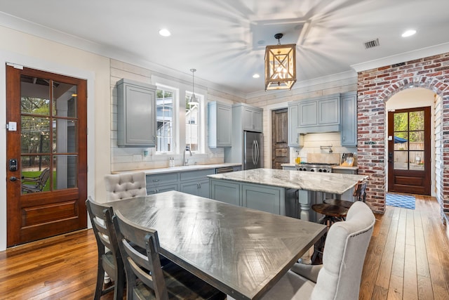 kitchen featuring a center island, light hardwood / wood-style flooring, hanging light fixtures, light stone countertops, and stainless steel fridge