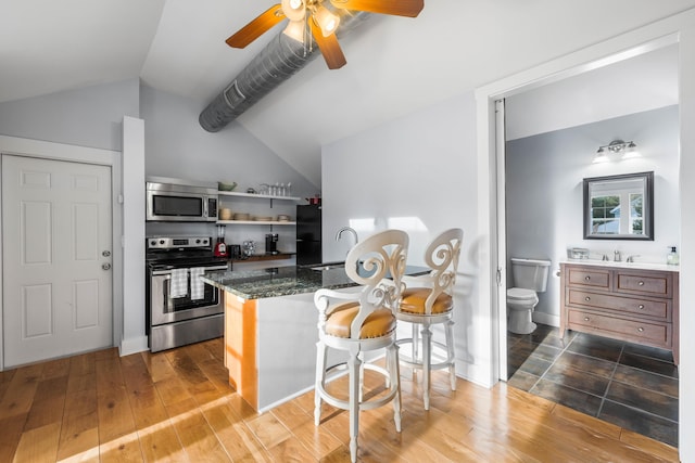 kitchen with lofted ceiling, appliances with stainless steel finishes, sink, and hardwood / wood-style flooring