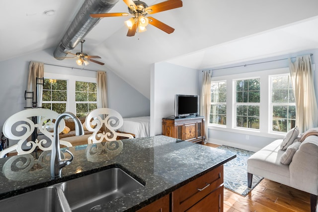 kitchen with light hardwood / wood-style floors, ceiling fan, lofted ceiling, dark stone counters, and sink