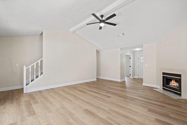 unfurnished living room with lofted ceiling with beams, a tile fireplace, ceiling fan, and light hardwood / wood-style flooring