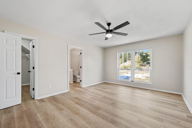 unfurnished bedroom featuring light hardwood / wood-style flooring, ceiling fan, ensuite bathroom, a spacious closet, and a closet