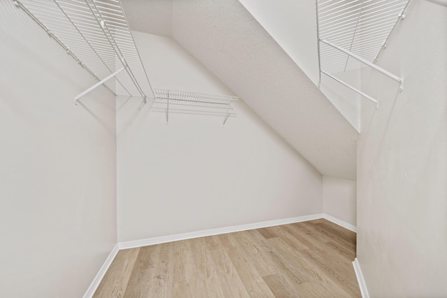 spacious closet with vaulted ceiling and light hardwood / wood-style floors