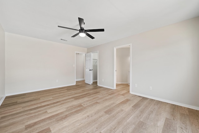 unfurnished bedroom with a walk in closet, light hardwood / wood-style floors, a closet, and ceiling fan