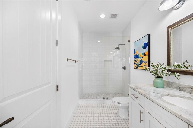 bathroom featuring vanity, tiled shower, and toilet