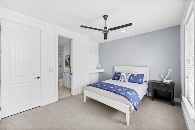 carpeted bedroom with ceiling fan, ensuite bath, and multiple windows