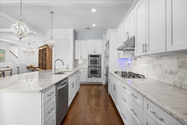 kitchen with sink, white cabinetry, hanging light fixtures, appliances with stainless steel finishes, and a kitchen island with sink