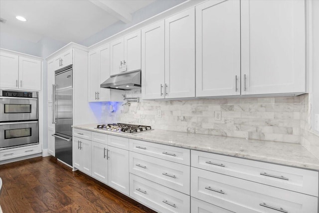 kitchen featuring dark hardwood / wood-style floors, white cabinetry, backsplash, light stone counters, and stainless steel appliances