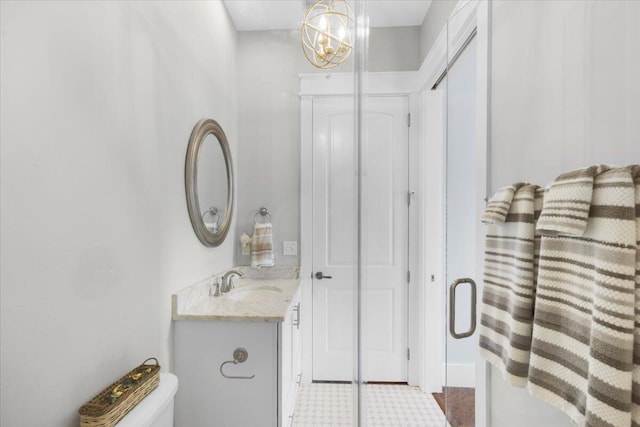 bathroom with vanity, toilet, and a notable chandelier