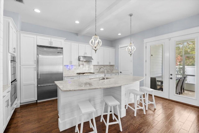 kitchen featuring white cabinetry, appliances with stainless steel finishes, a kitchen island with sink, and sink