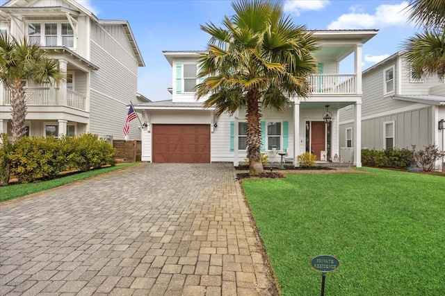 view of front of home featuring a garage, a balcony, and a front lawn