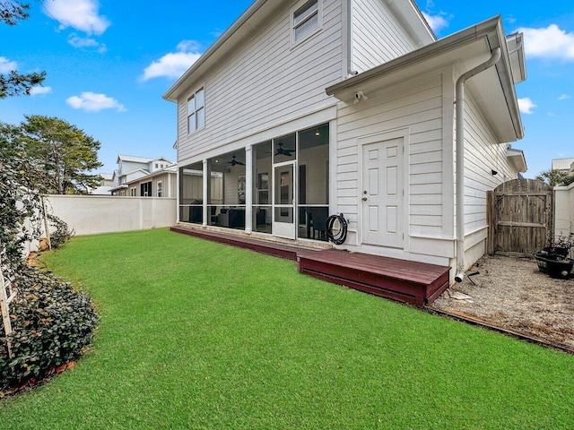 back of property with ceiling fan, a yard, and a sunroom