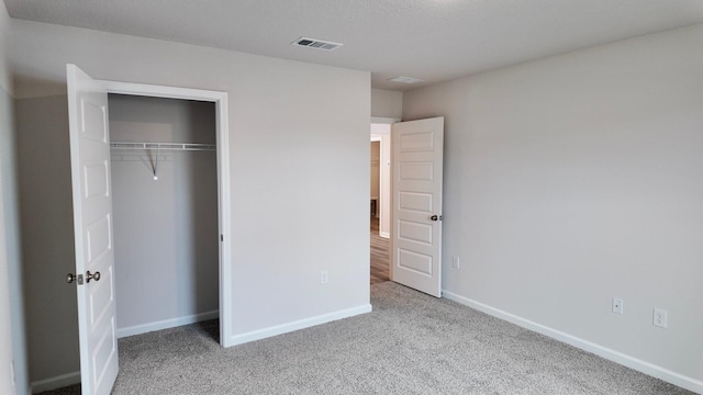 unfurnished bedroom with light colored carpet and a closet