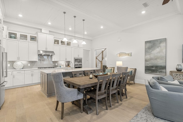 dining space featuring sink, light hardwood / wood-style flooring, ornamental molding, and beamed ceiling