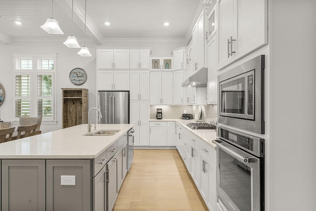 kitchen featuring white cabinets, appliances with stainless steel finishes, pendant lighting, and a center island with sink