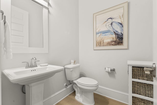 bathroom with toilet, heating unit, and hardwood / wood-style flooring