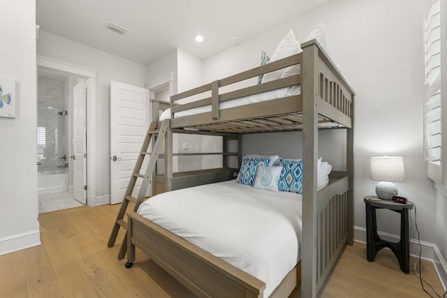 bedroom with ensuite bathroom and light hardwood / wood-style flooring