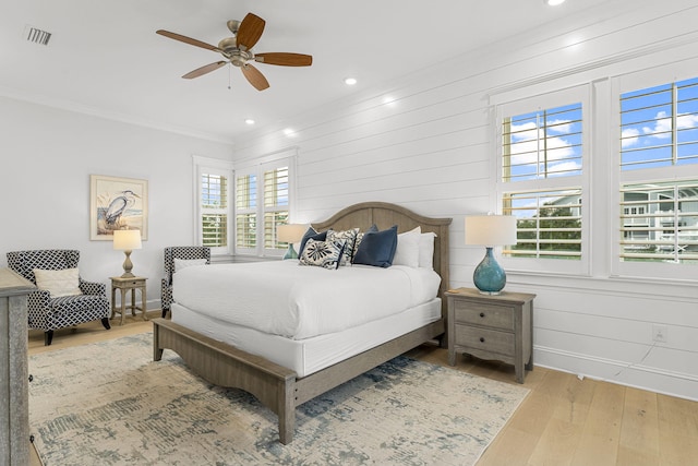 bedroom with ceiling fan, crown molding, and light hardwood / wood-style flooring