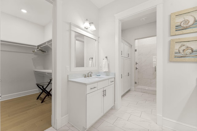 bathroom featuring a shower with shower door and vanity