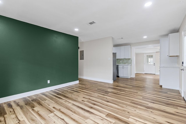 unfurnished living room with electric panel and light wood-type flooring