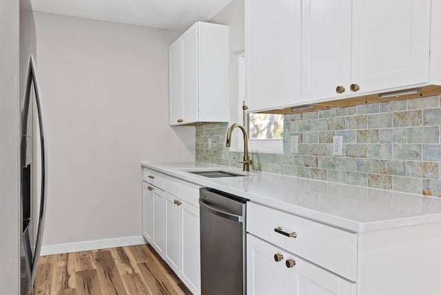 kitchen with sink, appliances with stainless steel finishes, white cabinets, decorative backsplash, and light wood-type flooring