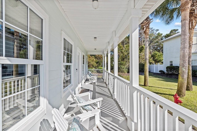 wooden terrace with a lawn and covered porch