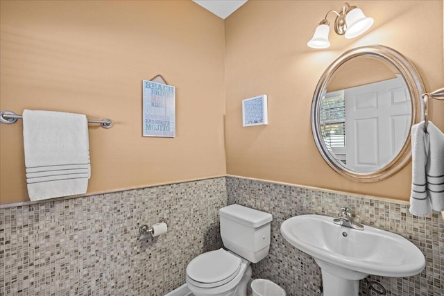 bathroom with sink, tile walls, and toilet