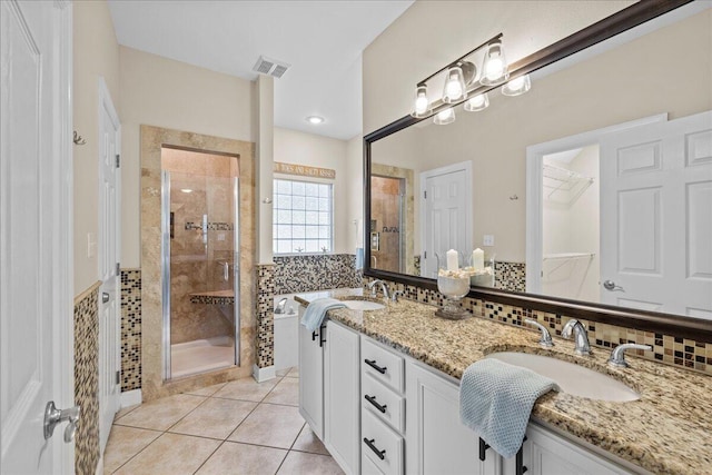 bathroom with decorative backsplash, tile patterned flooring, a shower with door, and vanity