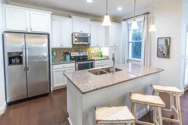 kitchen featuring a kitchen bar, appliances with stainless steel finishes, light stone countertops, pendant lighting, and sink