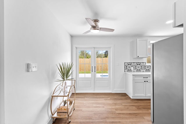 kitchen with ceiling fan, white cabinets, stainless steel fridge, and tasteful backsplash