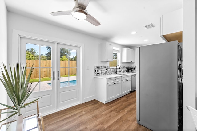 kitchen with decorative backsplash, sink, white cabinetry, appliances with stainless steel finishes, and french doors