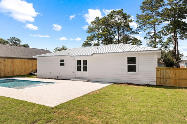 rear view of house with a fenced in pool, a yard, and a patio