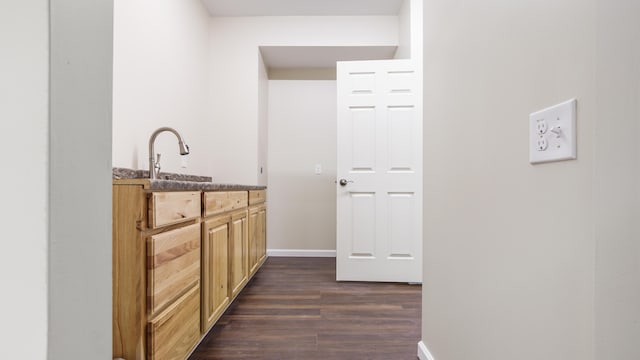 bar featuring dark hardwood / wood-style flooring, sink, and light brown cabinets