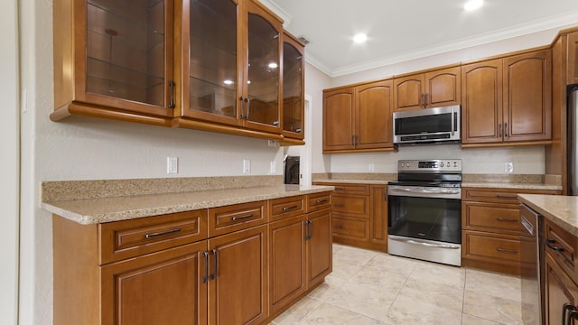 kitchen with crown molding, light tile patterned flooring, light stone countertops, and appliances with stainless steel finishes