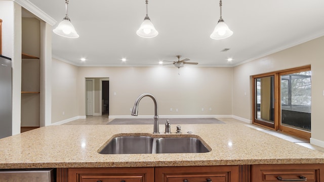 kitchen featuring hanging light fixtures, sink, and light stone counters