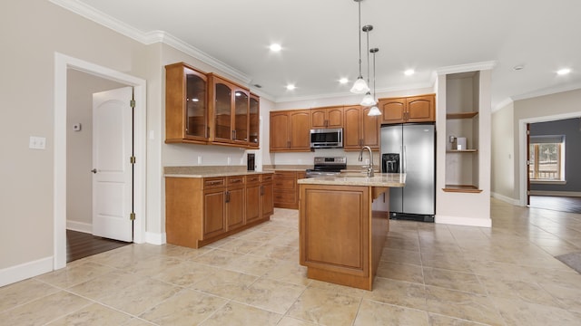 kitchen with appliances with stainless steel finishes, a kitchen island with sink, hanging light fixtures, light stone counters, and ornamental molding