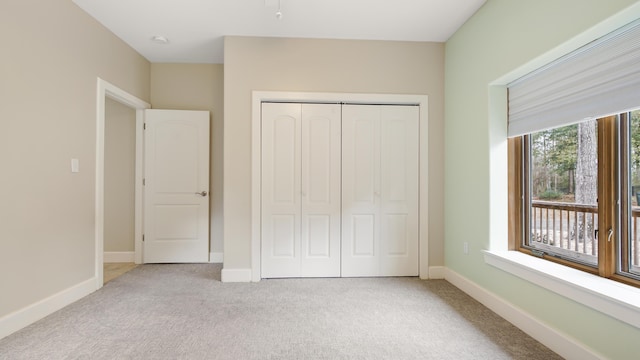 unfurnished bedroom featuring light colored carpet and a closet