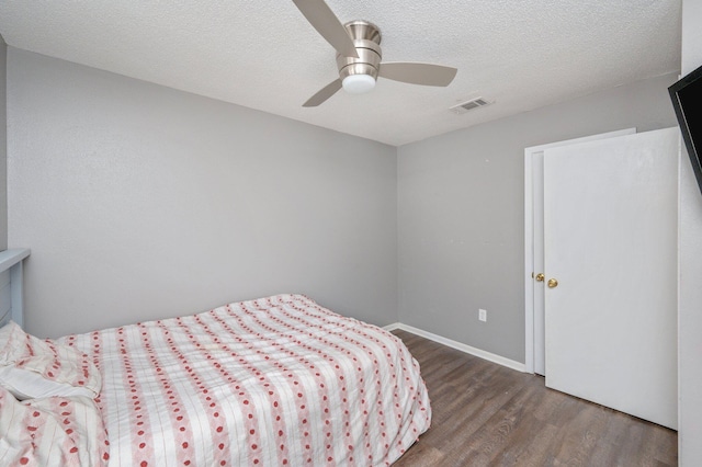 bedroom with ceiling fan, dark hardwood / wood-style floors, and a textured ceiling