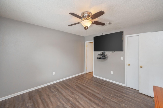 unfurnished bedroom with ceiling fan, dark hardwood / wood-style flooring, and a textured ceiling